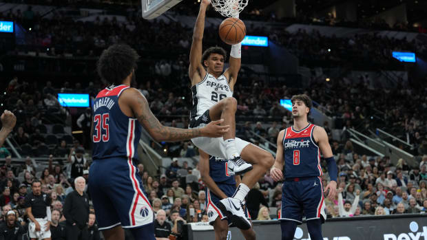 Jan 29, 2024; San Antonio, Texas, USA; San Antonio Spurs forward Dominick Barlow (26) dunks between Washington Wizards forwards Marvin Bagley III (35) and Deni Avdija (8) in the first half at Frost Bank Center.